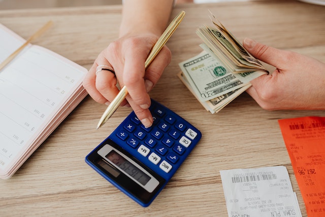 person counting cash and using a calculator to add it up